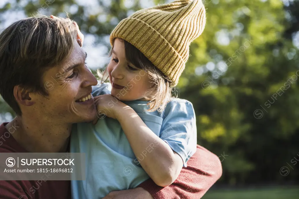 Father embracing son wearing knit hat in park