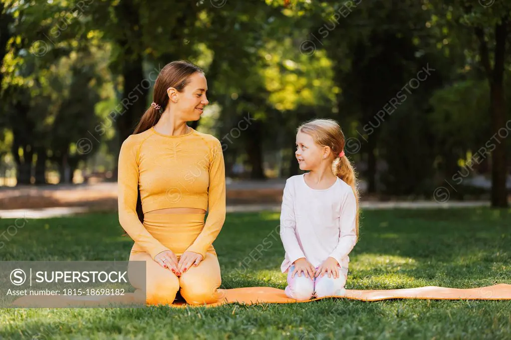 Smiling mother and daughter looking at each other in public park