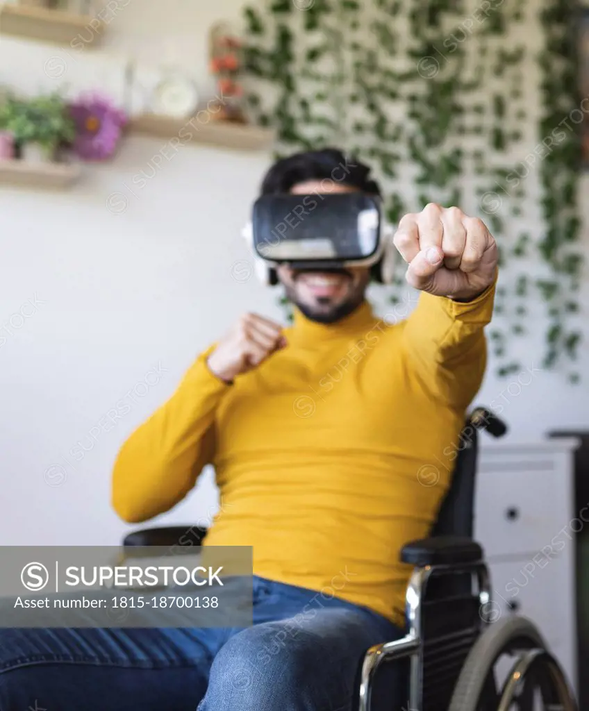 Smiling disable man wearing virtual reality headset punching at home
