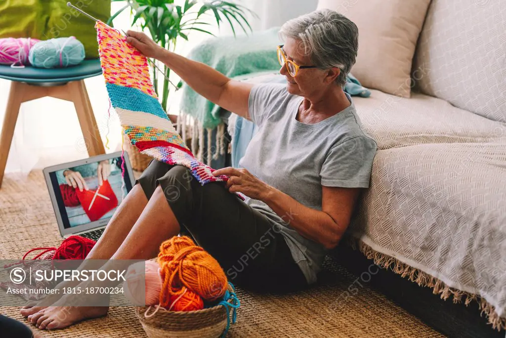 Woman with laptop checking knitted wool at home