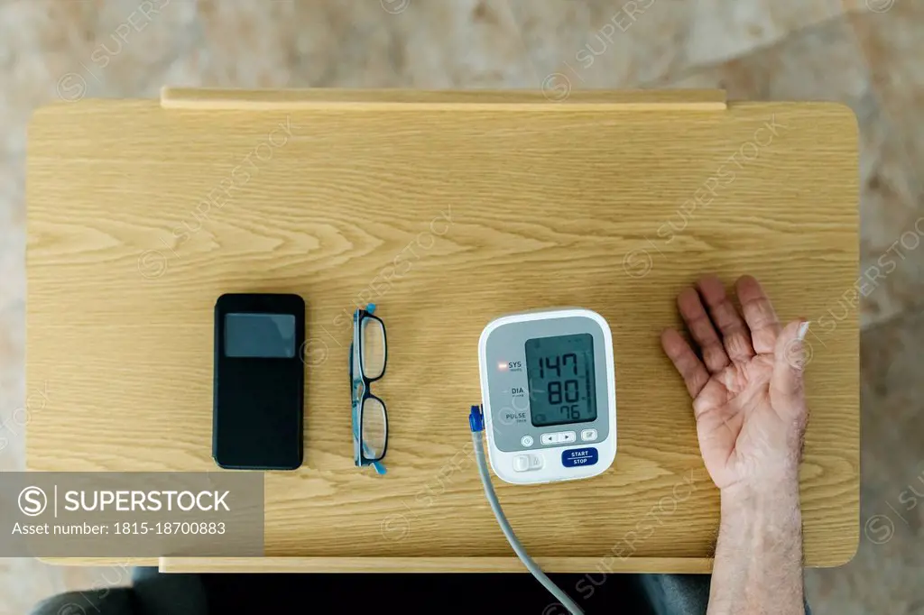 Man checking blood pressure on table at home