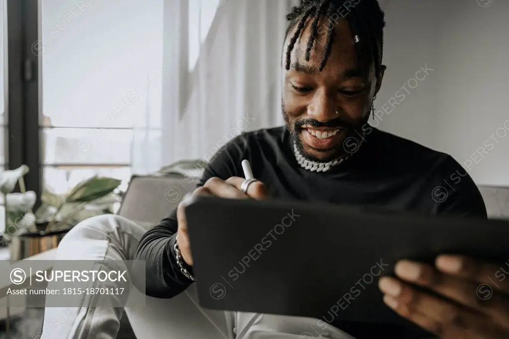 Smiling man using tablet PC at home
