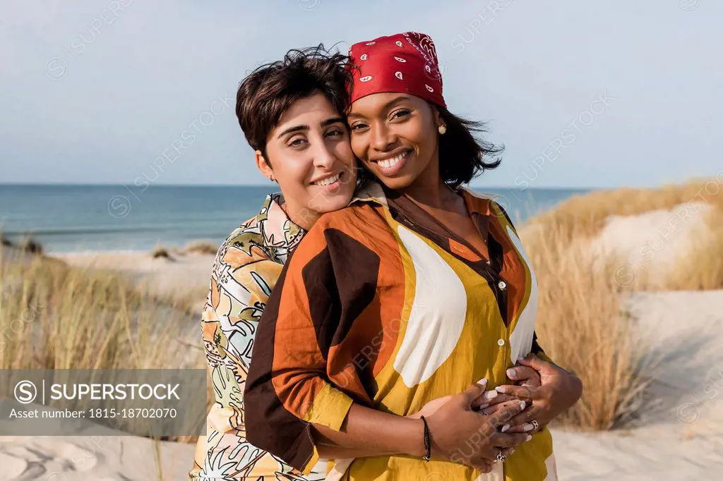 Affectionate lesbian couple embracing at beach on sunny day