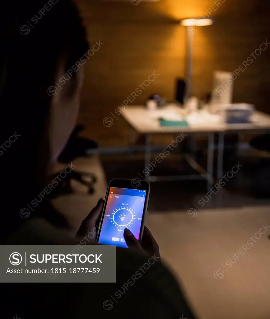 Woman using light bulb icon mobile phone screen at home