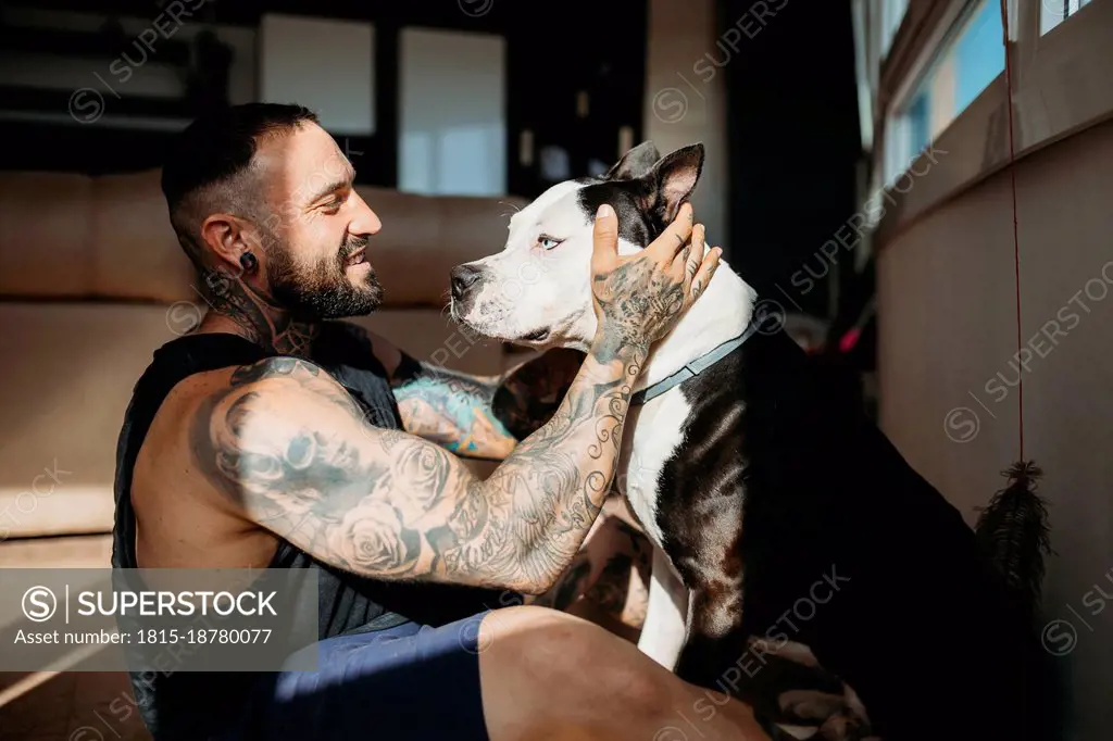 Smiling man sitting with dog at home