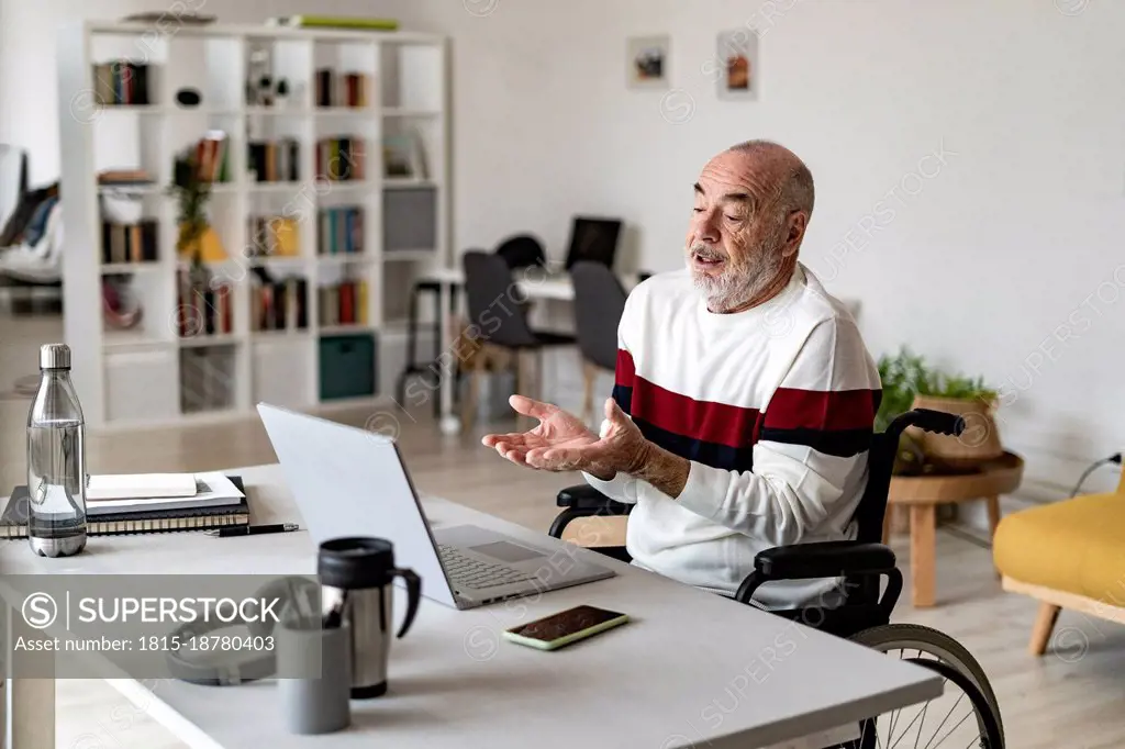 Senior businessman talking to video call through laptop on table