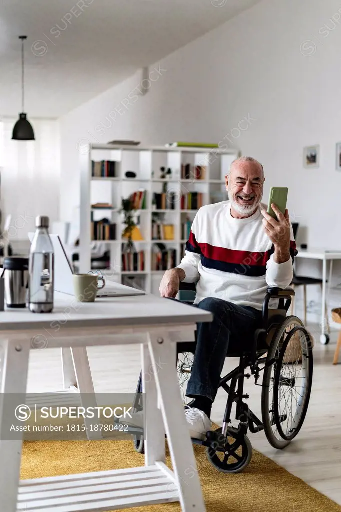 Businessman on wheelchair attending video call through mobile phone at home