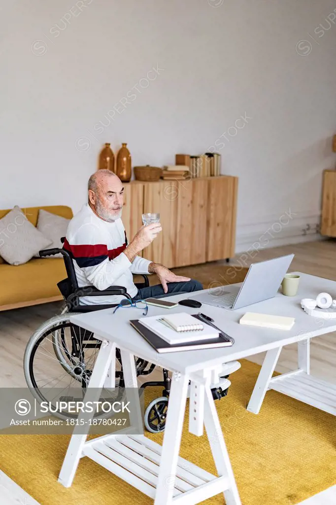 Senior businessman sitting on wheelchair at home office
