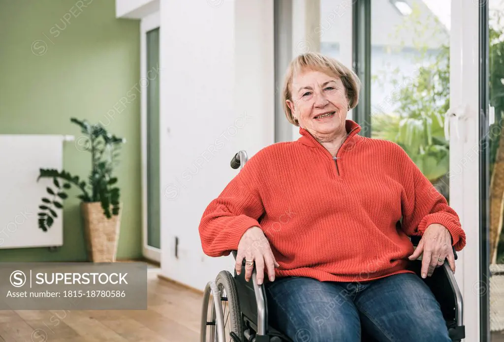 Smiling disabled woman in wheelchair at home