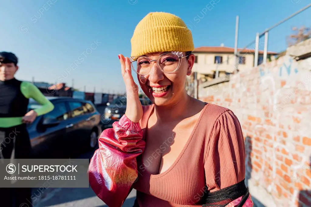Happy woman with knit hat and sunglasses on footpath