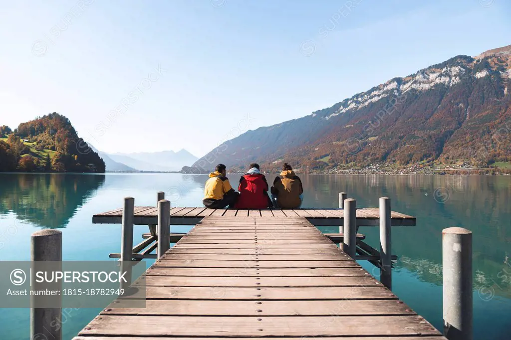 Friends sitting on pier and looking at mountains at Interlaken, Switzerland