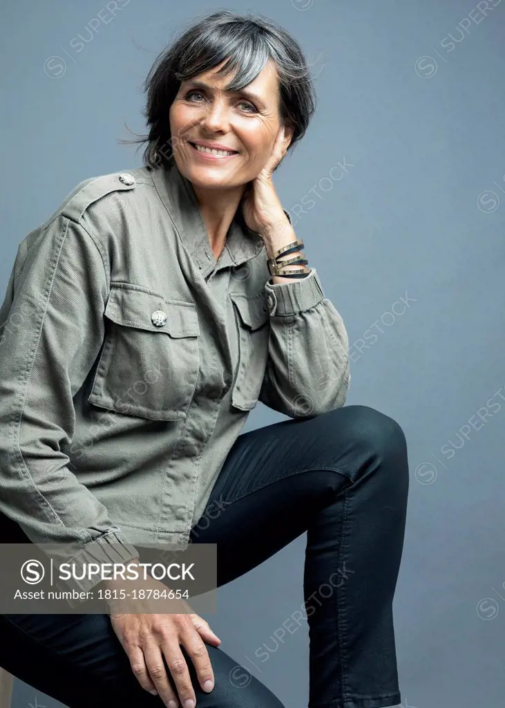 Smiling woman in casuals against gray background