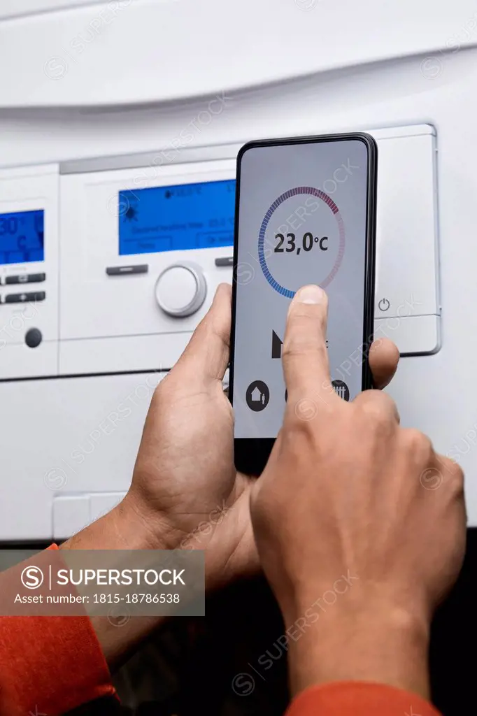 Man adjusting boiler temperature through mobile phone at home