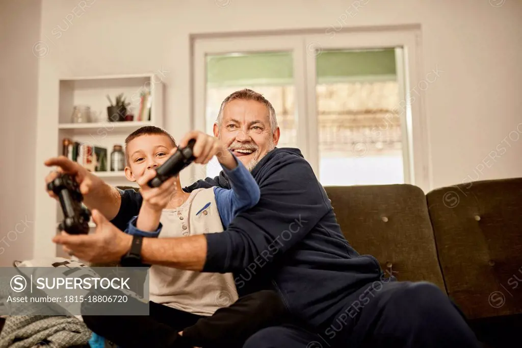 Grandfather and grandson enjoying playing video game at home