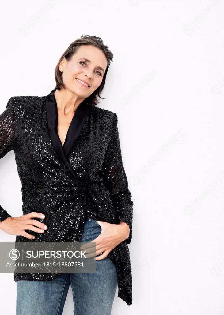 Smiling woman with hand in pocket against white background