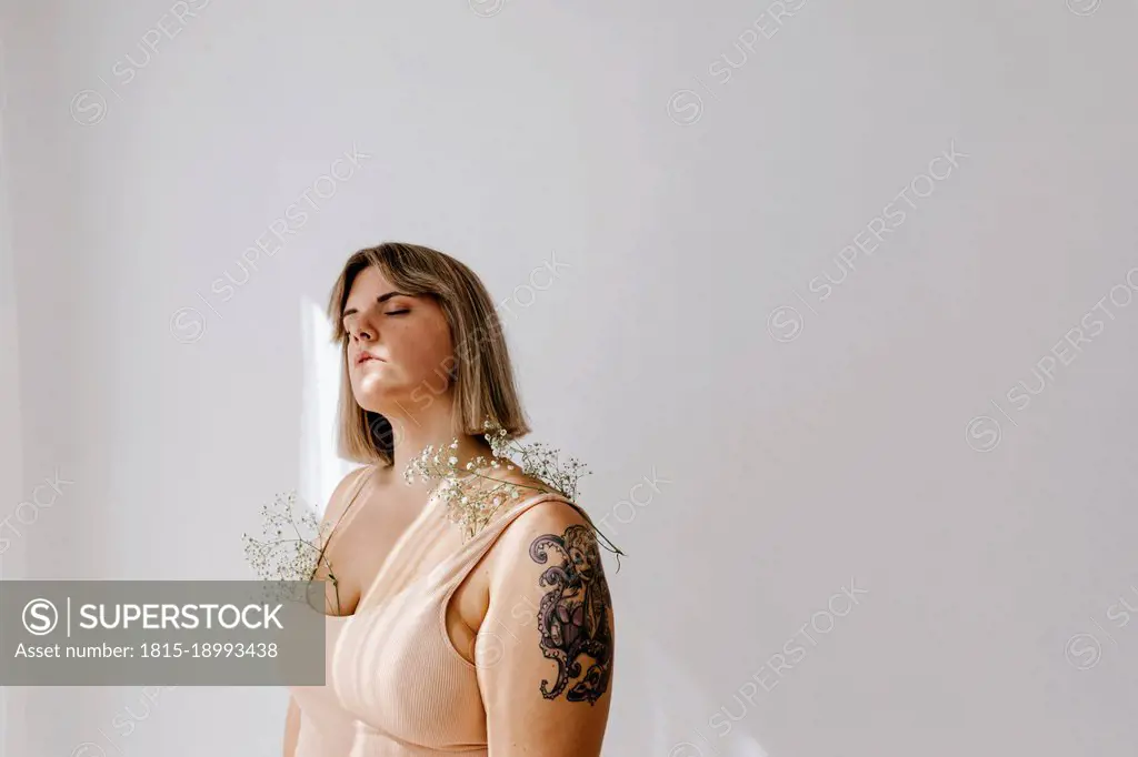 Young curvy woman with flowers on shoulder