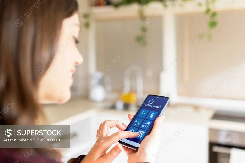 Young woman using smart home application on mobile phone at home