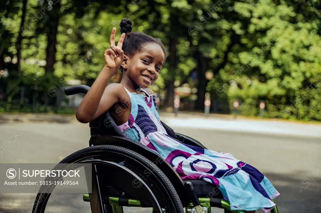 Disabled girl in wheelchair making peace sign
