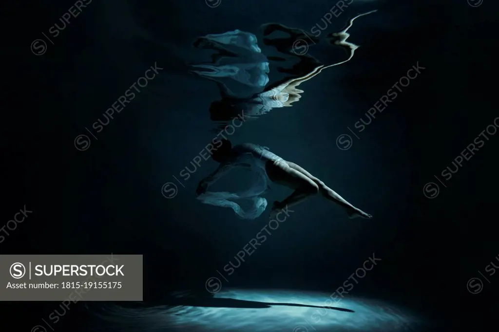 Young woman with reflection swimming undersea