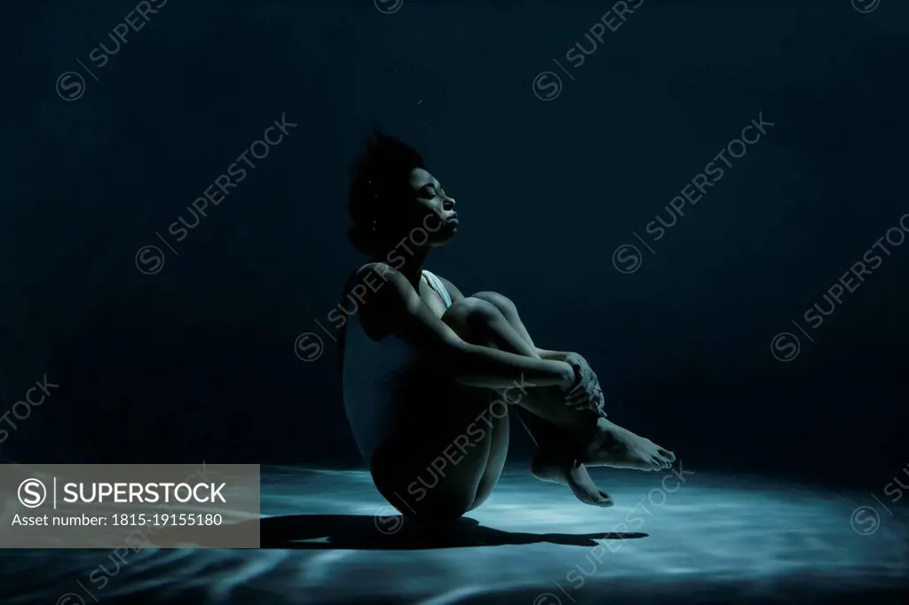 Young woman swimming in fetal position undersea