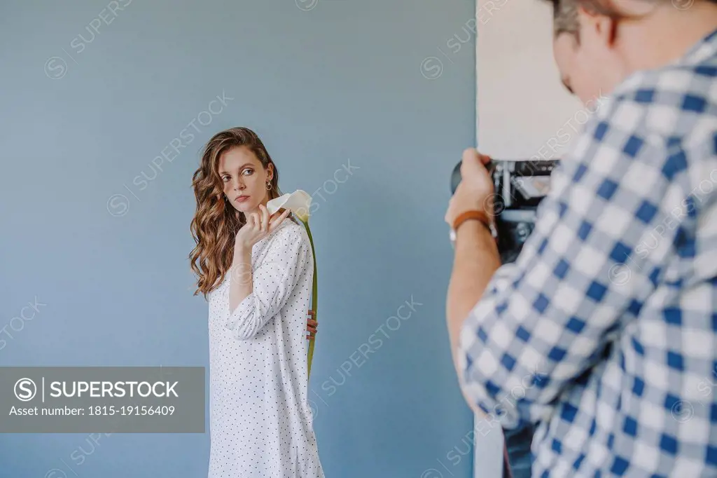 Photographer taking woman's picture standing by wall