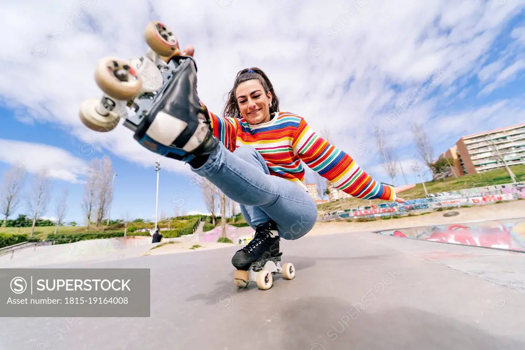 Smiling woman roller skating in skateboard park on sunny day