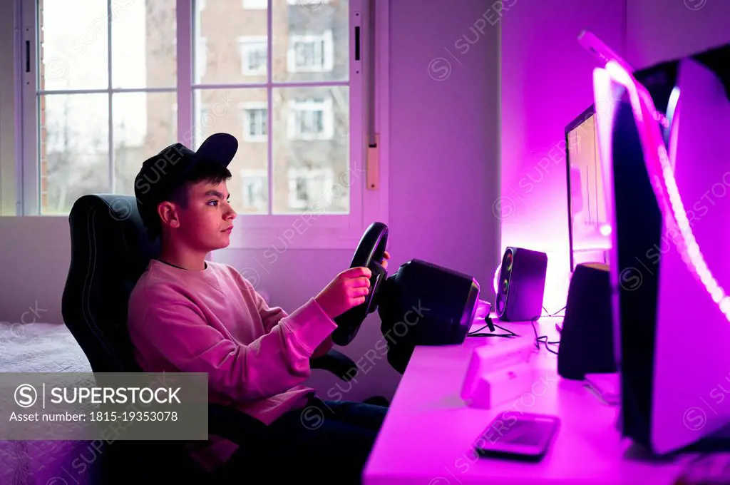 Boy playing video game on computer in bedroom at home