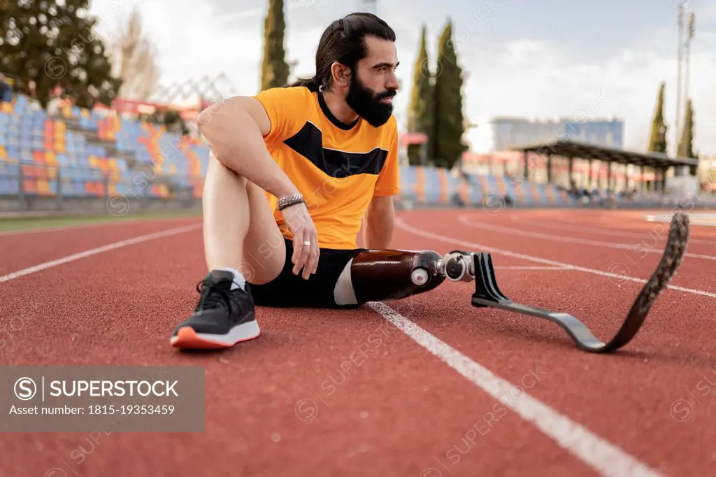 Athlete with prosthetic leg sitting on running track
