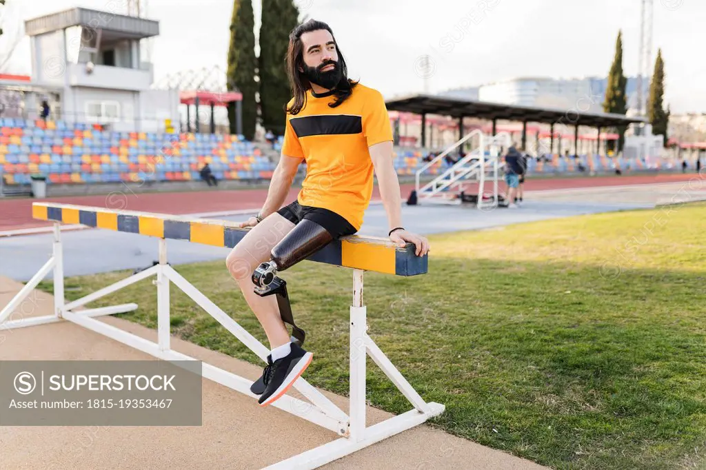 Man with prosthetic leg sitting on hurdle