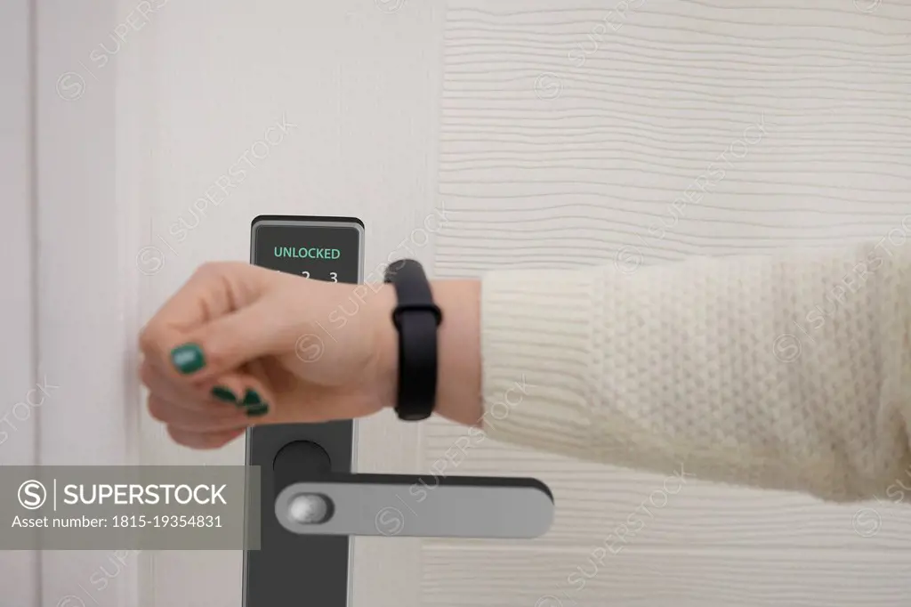 Woman scanning smart watch to open door of house