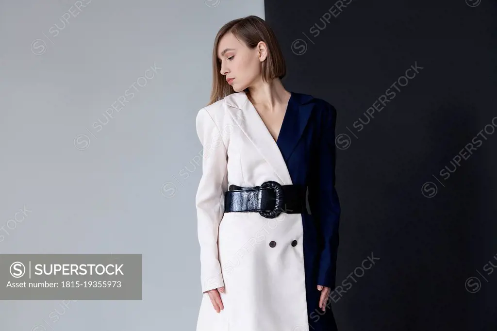Fashionable woman standing against dual toned background