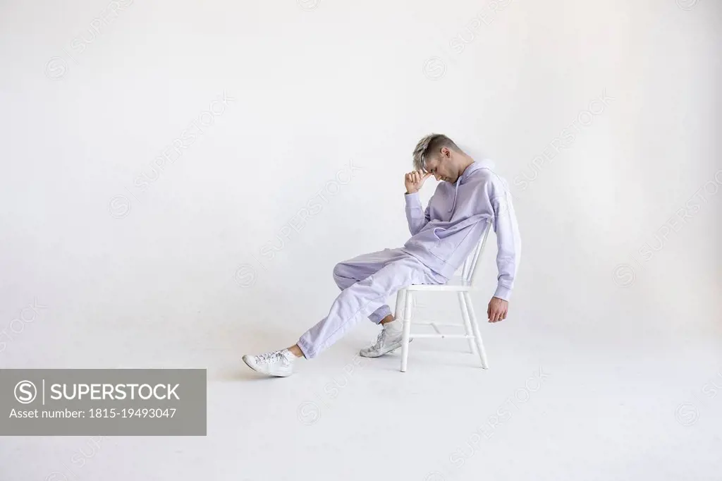 Stressed young man sitting on chair against white background