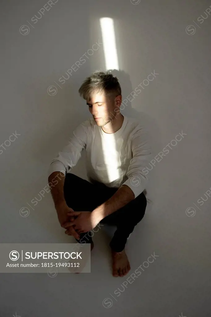 Stressed young man with beam of light on face