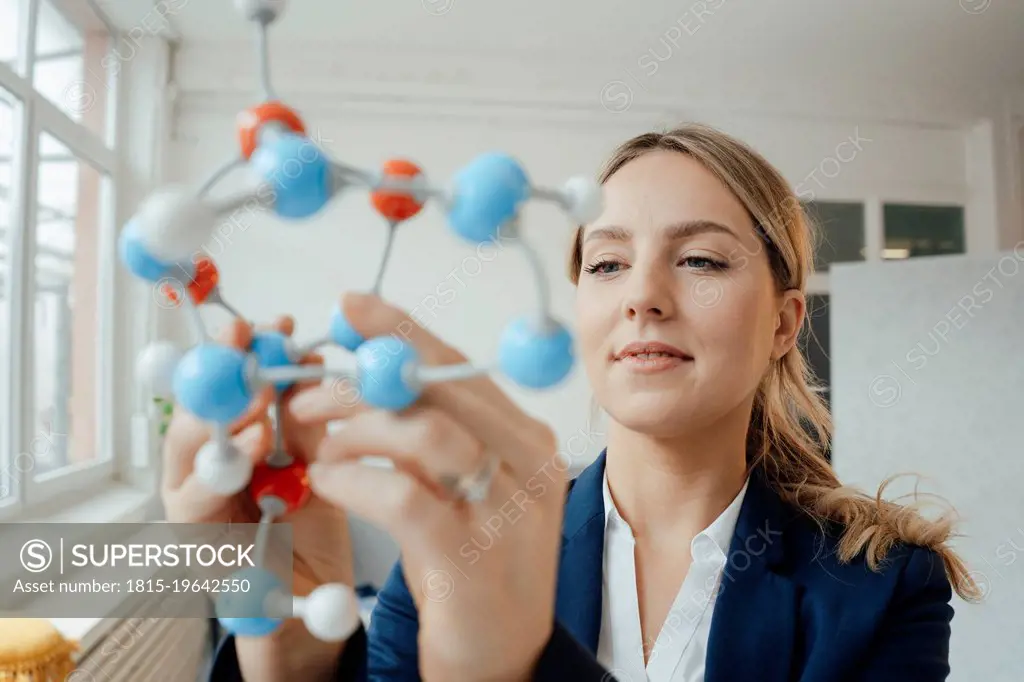 Beautiful businesswoman analyzing molecular model in office