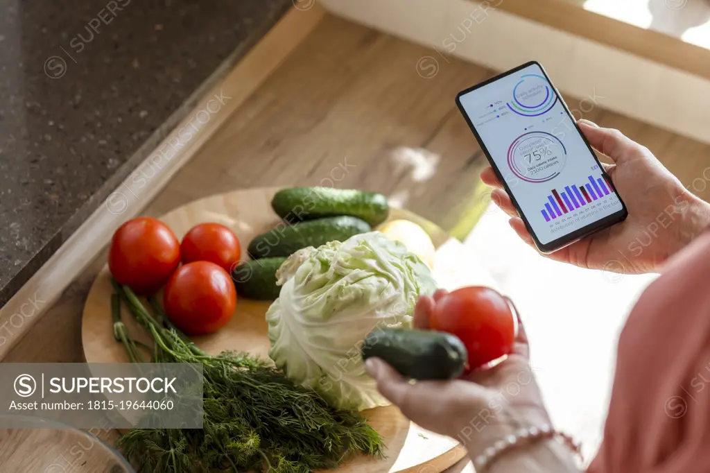 Woman holding smartphone with mobile app and vegetables