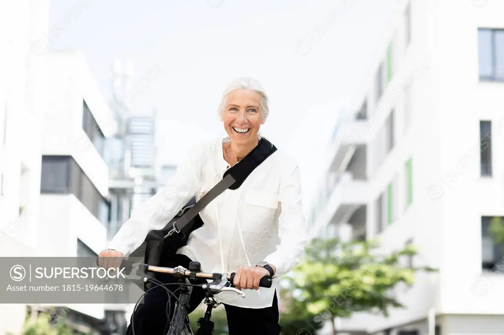 Happy businesswoman commuting to work through bicycle