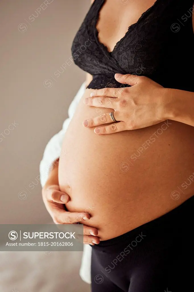 Hands of pregnant woman touching stomach at home