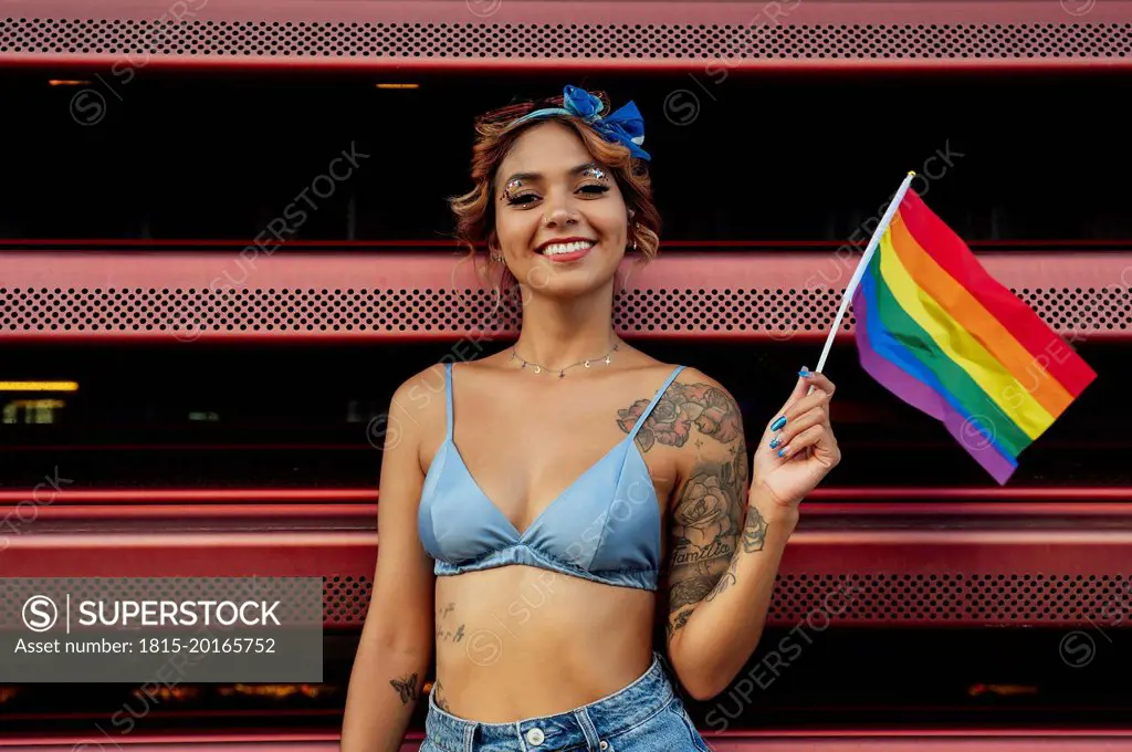 Woman holding rainbow flag in front of shutter