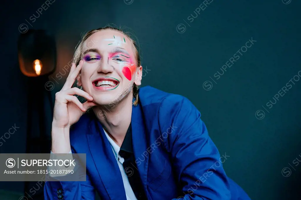 Smiling man with make-up in front of wall