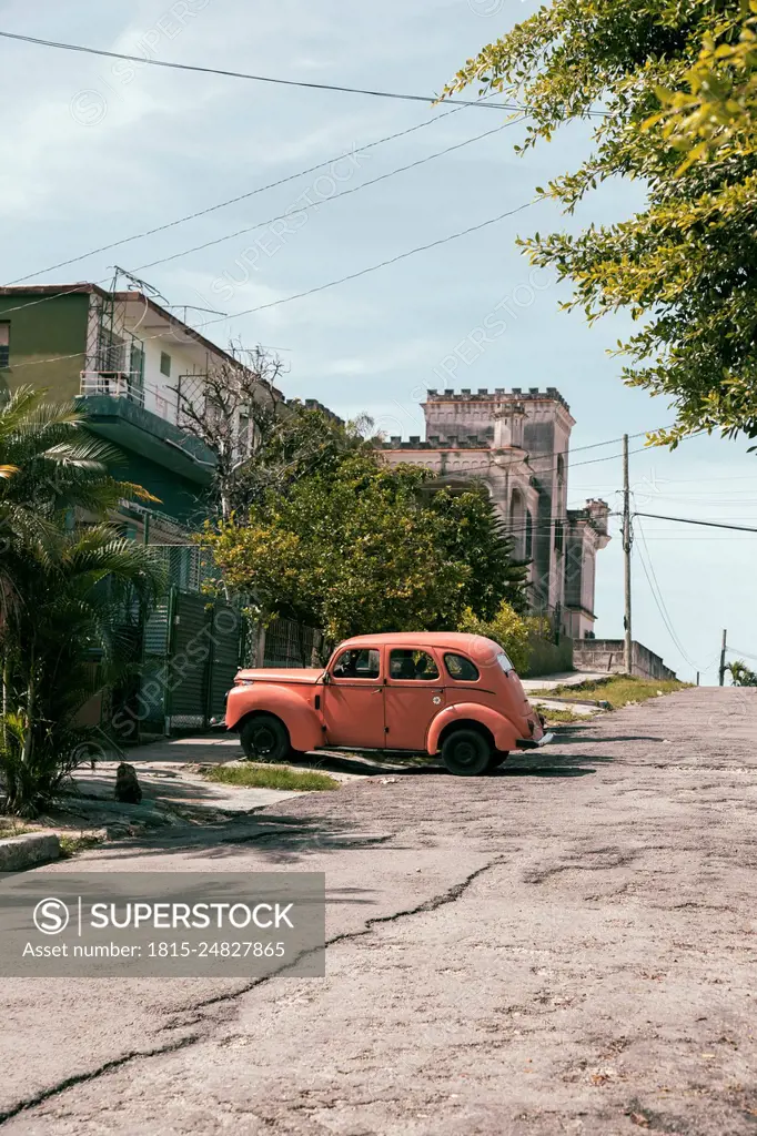 Cuba, Havana, Peach colored vintage car parked along street in La Vibora neighborhood