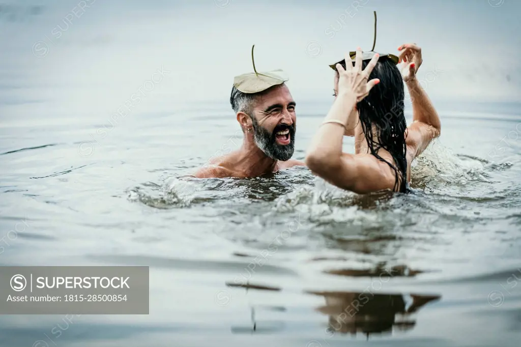 Happy mature man with woman having fun together in lake