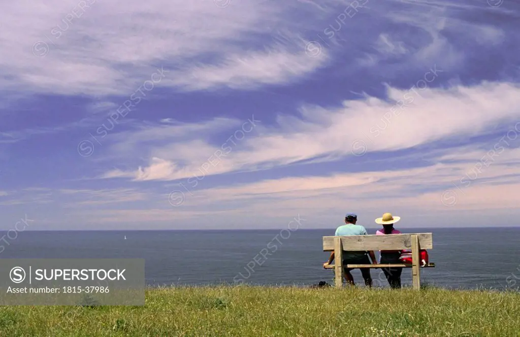 New Zealand, Couple sitting on bench at seafront of Kaikoura