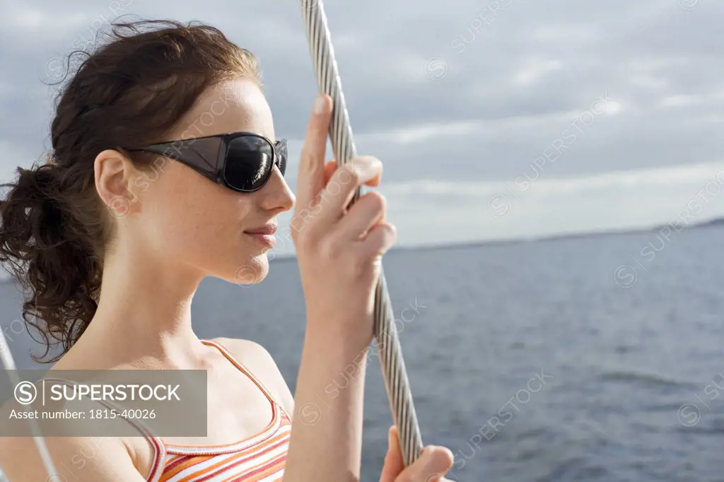Germany, Baltic Sea, Lübecker Bucht, Young woman standing on deck of yacht, smiling, portrait