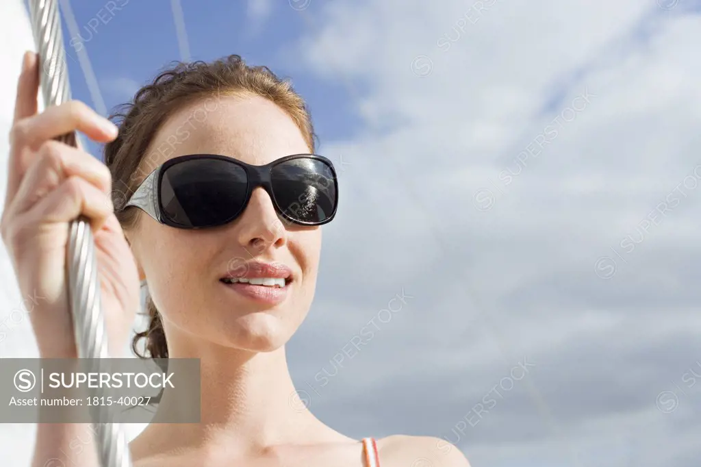 Germany, Baltic Sea, Lübecker Bucht, Young woman standing on deck of yacht, smiling, portrait