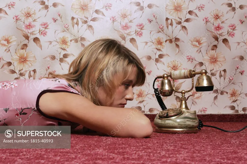 Young woman lying on floor, looking at telephone