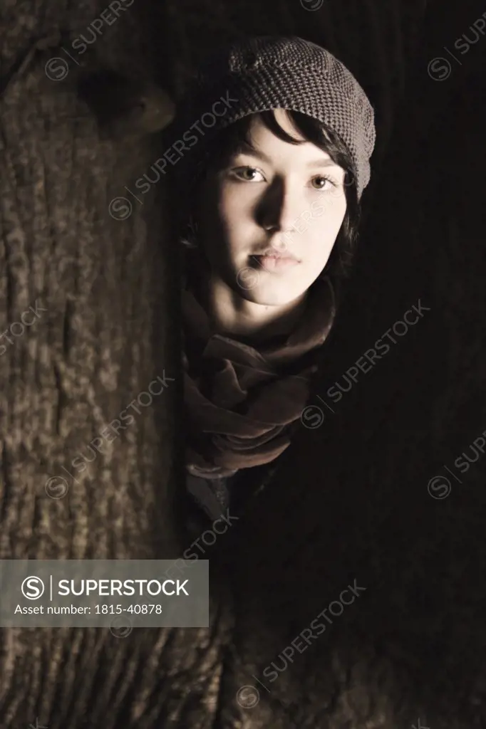 Young woman standing between tree trunk