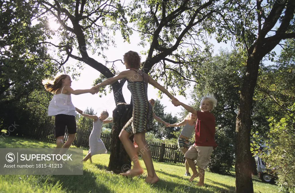 Children dancing around a tree