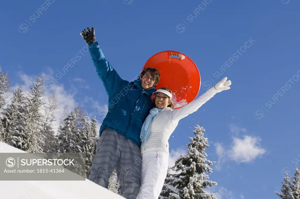 Austria, Salzburger Land, Altenmarkt-Zauchensee, Young couple in snow, waving hands, smiling, portrait