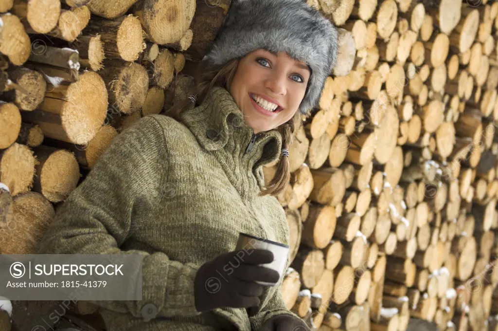 Austria, Salzburger Land, Altenmarkt, Young woman leaning against stacked firewood