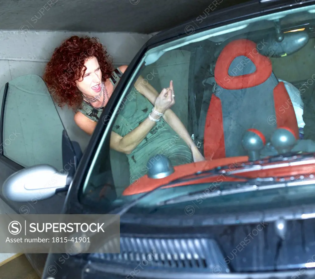 Woman entering car, making rude hand gesture